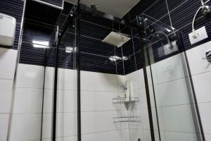 um chuveiro numa casa de banho com azulejos pretos e brancos em Deoni apartment em Tirana