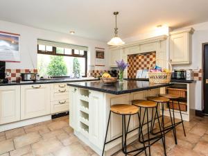 a kitchen with white cabinets and a island with bar stools at Aryarch in Eglingham