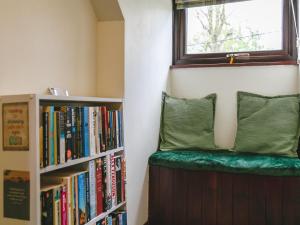 a book shelf with a green bench next to a window at Aryarch in Eglingham