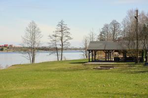 a pavilion on a grassy hill next to a lake at Ośrodek Wypoczynkowy A26 - Mazury in Ełk