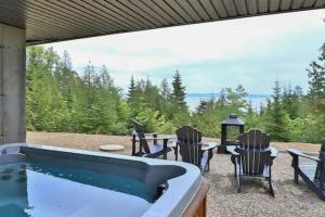 a patio with a hot tub and chairs and a table at Cabine A in Petite-Rivière-Saint-François