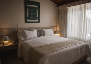 a bedroom with a large white bed and a window at Hotel Ponta Verde Praia do Francês in Praia do Frances