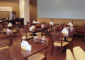 une salle à manger avec des tables et des chaises en bois dans l'établissement MainStay Suites Meridian, à Meridian