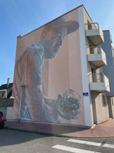 un gran mural de un hombre sosteniendo una bebida en Magnifique Studio Calais Plage en Calais