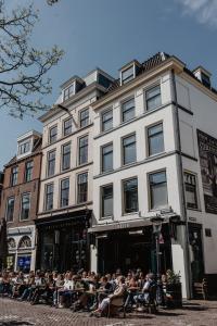 una multitud de personas sentadas fuera de un edificio en Mother Goose Hotel, en Utrecht