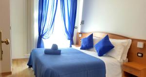 a bedroom with a blue bed with blue pillows and a window at Hotel Mare Blu -- boutique in Pineto