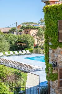 a swimming pool with lounge chairs next to a building at Hotel Shegara in Porto-Vecchio