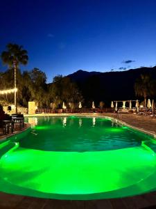 una piscina verde di notte con montagne sullo sfondo di Hotel Berke Ranch&Nature a Kemer