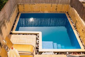 una piscina con 2 sillas y una piscina en A charming Gozo Farmhouse in Sannat, en Sannat