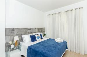 a white bedroom with a bed with blue sheets and pillows at Três Quartos, Gigante e confortável Próximo ao Hard Rock Café no Batel in Curitiba