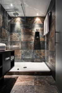 een badkamer met een douche en een bad bij M Hotel in Genk