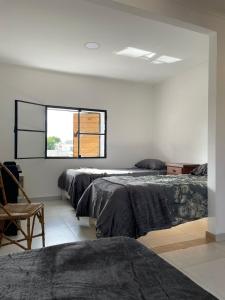 1 dormitorio con 3 camas y ventana en La Porteña en San Pedro