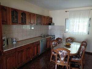 a kitchen with wooden cabinets and a table and chairs at Apartments Krivokapic in Bijela