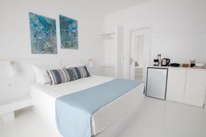 a white bedroom with a bed and a kitchen at Alloro Perissa in Perissa
