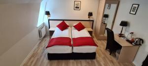 a bedroom with a bed with red pillows and a desk at Prinsen Hotel in Aalborg