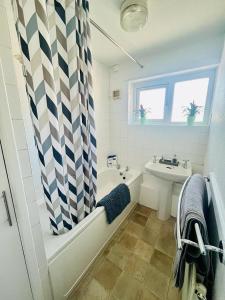 ein Badezimmer mit einem Duschvorhang, einer Badewanne und einem Waschbecken in der Unterkunft Barnstaple Drive House in Manchester