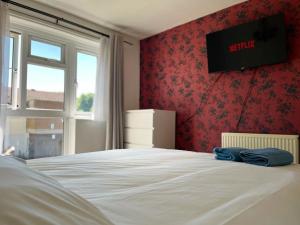 a bedroom with a bed with a television on the wall at Barnstaple Drive House in Manchester