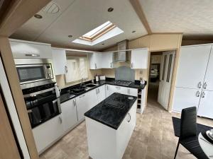 a kitchen with white cabinets and a black counter top at Ingoldmells Sunnymede I14 in Ingoldmells
