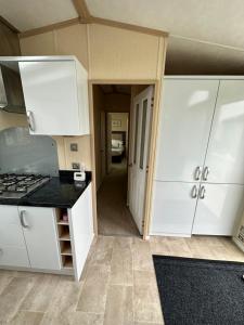 a kitchen with white cabinets and black counter tops at Sunnymede Ingoldmells Keyshare holiday lets in Ingoldmells