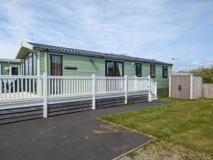 a green house with a white fence in front of it at 6 berth holiday home on Ocean Edge near Morecambe in Heysham