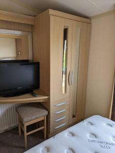 a bedroom with a bed and a tv and a cabinet at 6 berth holiday home on Ocean Edge near Morecambe in Heysham