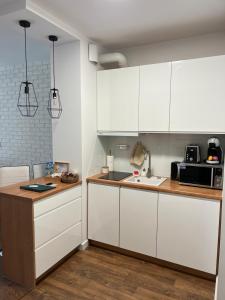 a kitchen with white cabinets and a sink at Sosnowe Apartamenty - Marina in Augustów