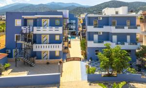een blauw appartementencomplex met bergen op de achtergrond bij Happy Days in Malia