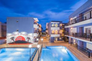 a hotel with a pool in front of a building at Happy Days in Malia