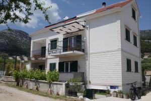 ein weißes Haus mit Balkonen und einem Zaun in der Unterkunft Apartments Sarbunal in Bol