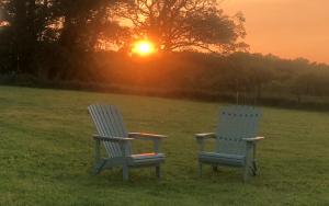 two chairs sitting in a field with the sunset in the background at Romantic Rural Break In Countryside Castle Grounds Private Retreat Wizards Rest in Bishops Tawton