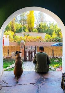 un hombre y un perro sentados en un arco en Familia Albahaca en Tilcara