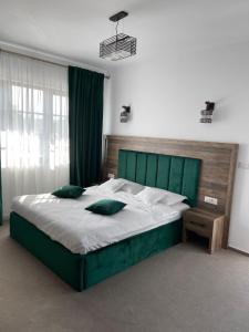 a bedroom with a large bed with a green headboard at Livada Bucovinei in Horodnic de Sus