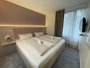 a bedroom with a large white bed with a television at Hotel Park Soltau in Soltau +26 photos