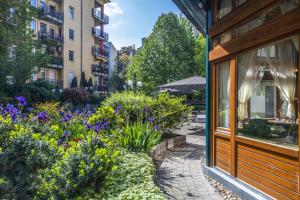 a garden in front of a building with flowers at Corvin Hotel Budapest Residence in Budapest