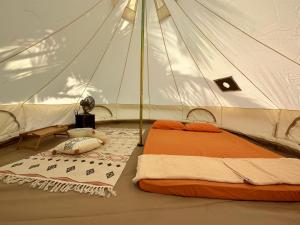 a bed in a white tent with a table in it at Beach N Breeze Glamping in Melaka