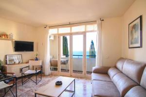 ein Wohnzimmer mit Couch und großem Fenster in der Unterkunft Apartamento con vistas al mar - Anfiteatro 18 in Calpe + 7 Fotos