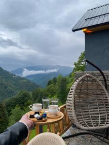 una persona che tiene un tavolo con bevande sul balcone di ELVA BUNGALOV a Çamlıhemşin