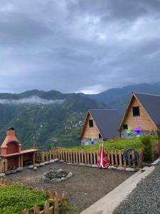 a couple of wooden cabins with a fence and mountains at ELVA BUNGALOV in Çamlıhemşin