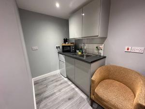 a kitchen with a counter and a sink and a chair at Luxury Detached Studio Apartment in Luton in Luton