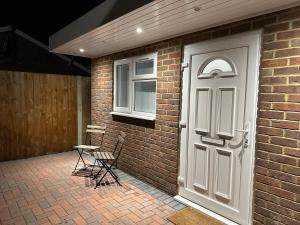 a brick building with a white door and two chairs at Luxury Detached Studio Apartment in Luton in Luton