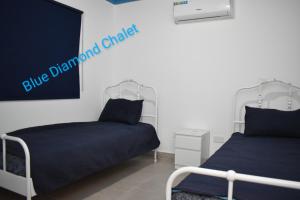 two beds in a room with a blue demand change sign at Blue Diamond in Jerash