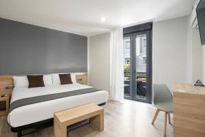 Un dormitorio con una cama y un escritorio y una ventana. en Albergue Alda Pilgrim Ponferrada, en Ponferrada