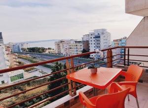 een rode tafel en stoelen op een balkon met uitzicht bij BEACH FRONT RIEM in Durrës