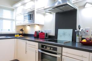 a kitchen with white cabinets and a black counter top at The Bay Filey in Filey