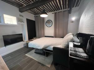 1 dormitorio con 1 cama y reloj en la pared en ROMEO Charmant Studio Centre Historique Grasse en Grasse