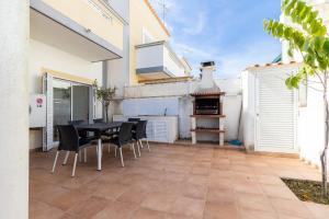 een patio met een tafel en stoelen en een pizza-oven bij Villa Amarela by AlgarveManta in Manta Rota