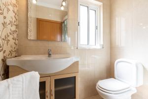 een badkamer met een wastafel, een toilet en een spiegel bij Villa Amarela by AlgarveManta in Manta Rota +25 foto's