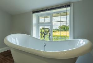 una vasca da bagno bianca in una stanza con finestra di Heath Cottage a Mattishall Altre 26 foto