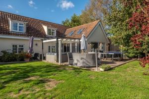 una casa con un cortile sul retro con un tavolo e un ombrellone di Heath Cottage a Mattishall