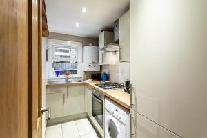 a kitchen with a stove and a washer and dryer at Charming Acton Dollhouse in London